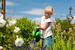 Kleines Mädchen gießt Blumen im Garten